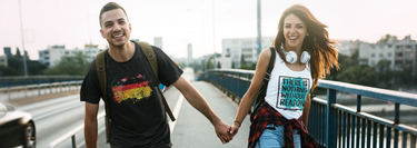 A stylish woman in a tank top and a man in a t-shirt, both featuring traditional German-inspired designs, showcasing intricate patterns and cultural elements